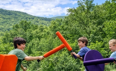 Kids having fun with foam fighting games with mountains in the background
