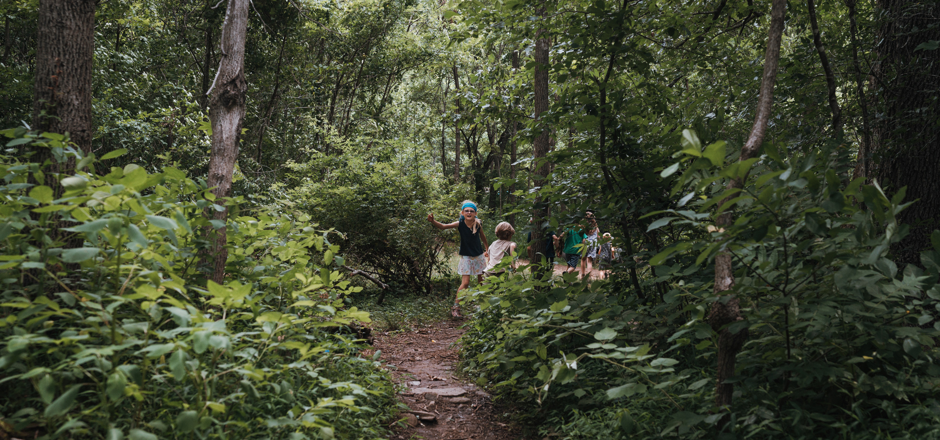A group of young campers head out into the woods for the day at Forest Floor summer camp