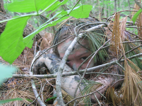 Child hiding in the woods at Asheville day camp for learning forest stealth