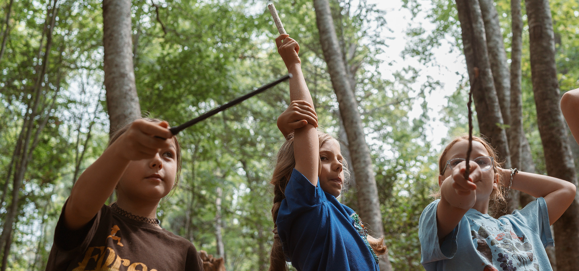 Children in role playing game at summer camp gather to point their magic wands skyward