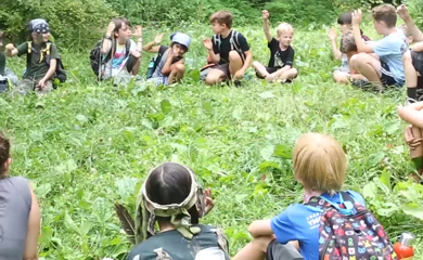 Forest kindergarten story telling session with children sitting in a clearing in the forest edge in a circle