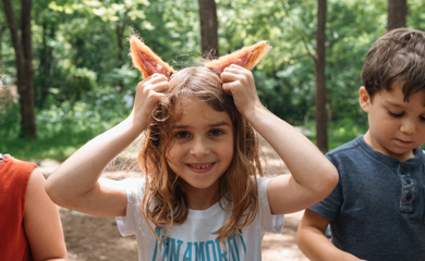 Children at homeschool class in forest show off their felted craft project animal ears