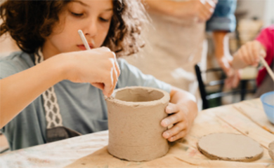 Homeschool pottery class with children working at table on handbuilding projects