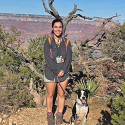 Outdoor educator Kayla Birstein hiking in the desert with her dog with red rock formations in the distance
