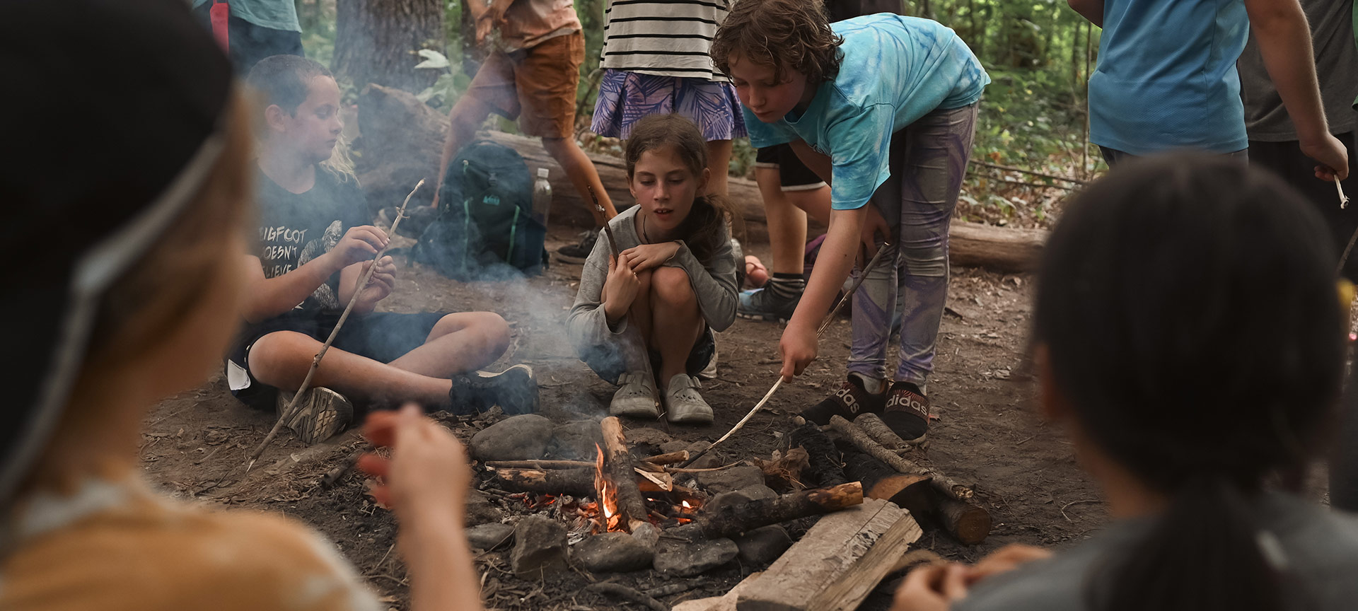 Group of kids roasting marshmallows and other snacks over a campfire near Asheville