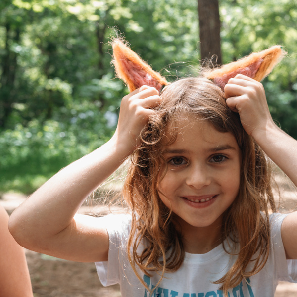 Young girl in the woods showing off her craft project felted coyote ears