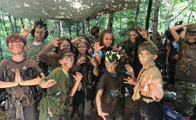 Group photo at nature camp of camoflauged and face painted kids at summer camp for stealth in forest