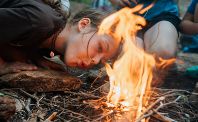 Girl leaning over starting a campfire and 