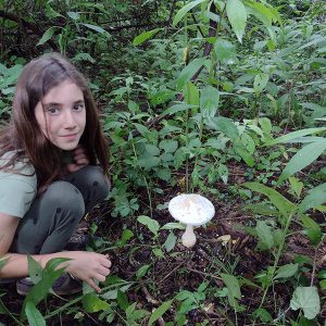 Teenage camper in forest at nature camp with discovery of giant mushroom
